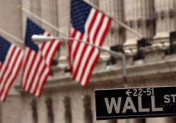 American flags hang outside the New York Stock Exchange (NYSE) behind the street sign on Wall Street in New York City.