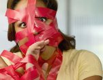 Businesswoman wrapped in red tape. (Occupational Licensing Graphic)