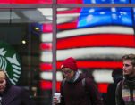 A woman pulls a hood over her head as she walks out of a Starbucks store into the cold wind at Times Square in New York, March 25, 2013. (Photo: Reuters)