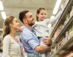 Sale, consumerism and people concept - happy family with child and shopping cart buying food at grocery store or supermarket. (Photo: PPD/AdobeStock/Syda Productions)