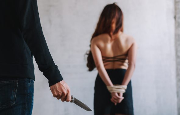 Kidnapping, human and sex trafficking concept of a female hostage and a man holding knife in an abandoned house. (Photo: AdobeStock)