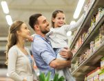 Sale, consumerism and people concept - happy family with child and shopping cart buying food at grocery store or supermarket. (Photo: PPD/AdobeStock/Syda Productions)