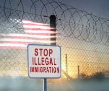 A graphic concept of barbed-wire, chain-linked fencing at the U.S. southern border with a sign reading, 