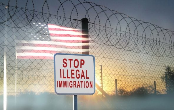 A graphic concept of barbed-wire, chain-linked fencing at the U.S. southern border with a sign reading, 